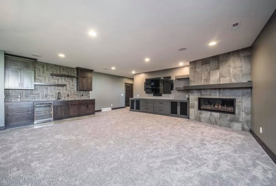 Finished basement family room with linear fireplace and stone surround