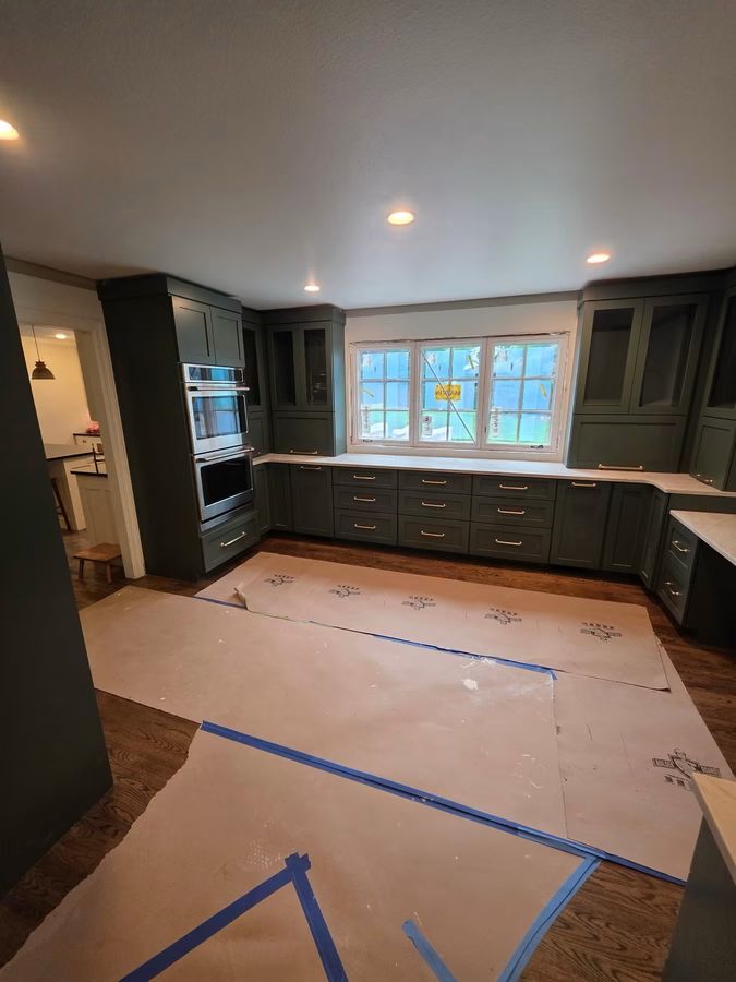 Custom kitchen remodel with deep green cabinetry and protected floors