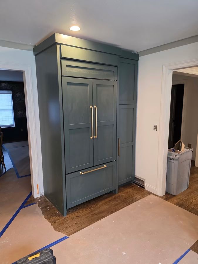 Panel-front refrigerator built into custom green cabinetry