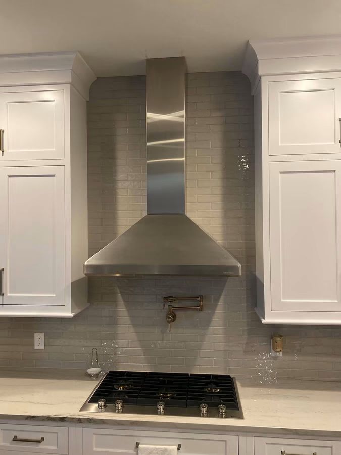 Stainless range hood and tile backsplash in a white custom kitchen