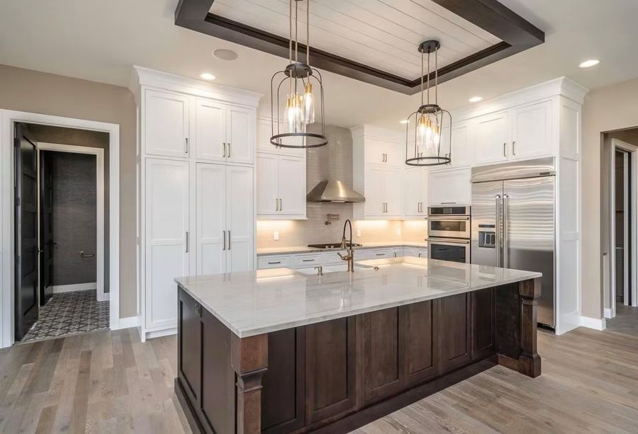 Custom kitchen with white perimeter cabinets, dark island and beamed ceiling