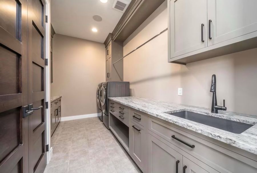 Custom laundry room with granite counter, utility sink and cabinetry