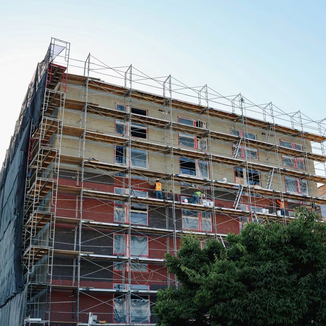 Multi-story building under construction with full perimeter scaffolding