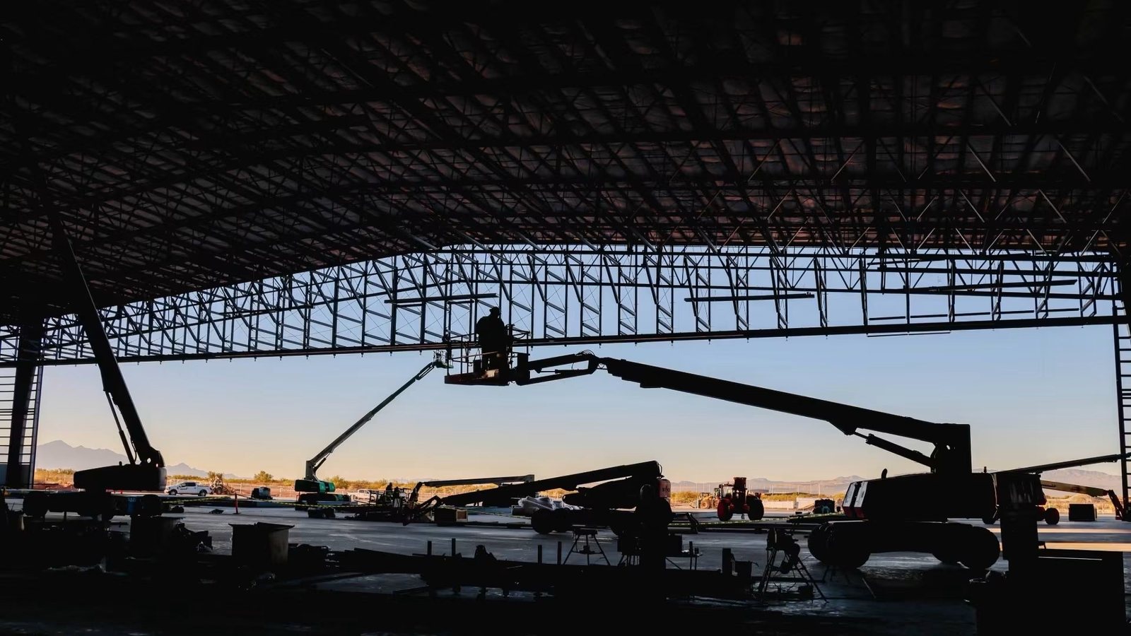 Steel building structure erected with equipment staged inside at sunset